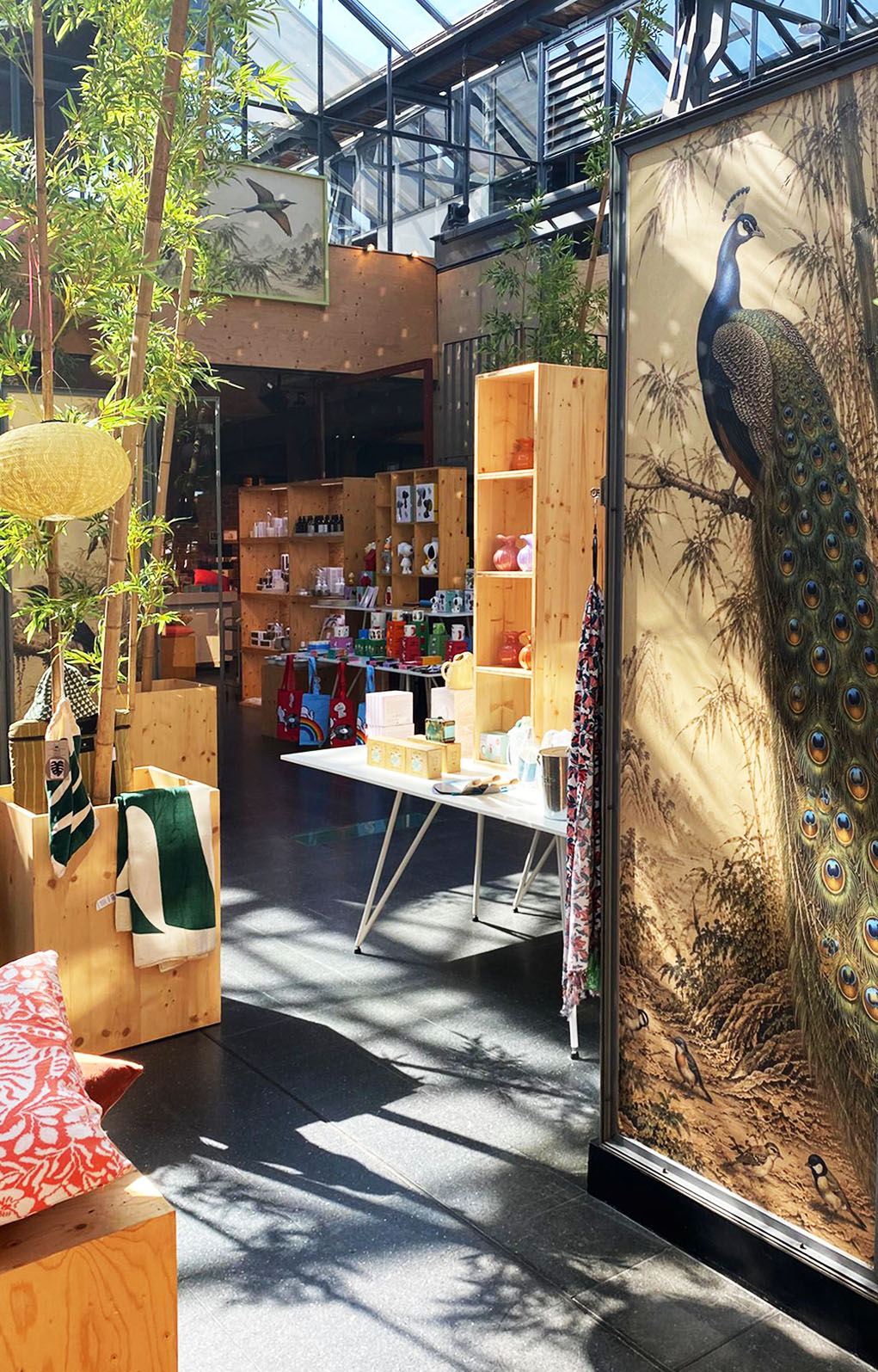 Blick in den BALLONI Store mit Pfau-Motiv, Holzregalen und farbenfroher Sommerdekoration